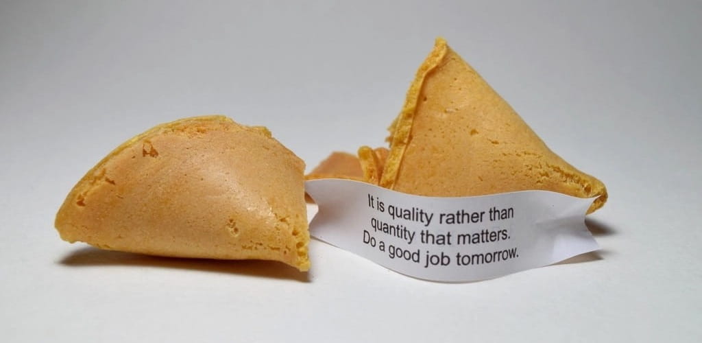 Una galleta de la suerte partida, con el papelito del mensaje a la vista.